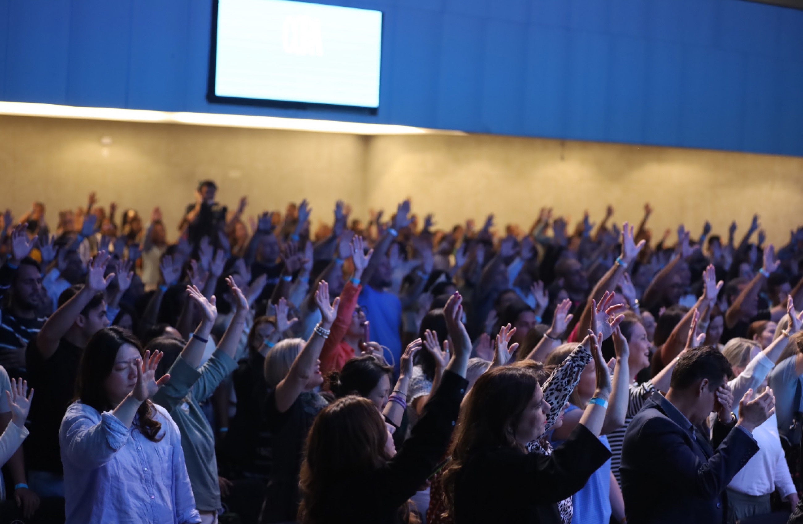 A crowd worshipping with hands raised