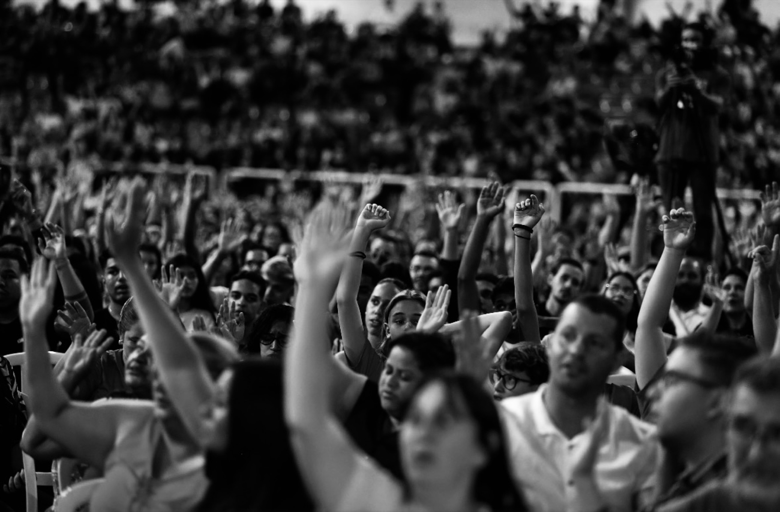 A packed arena of people gathered for worship, in black and white